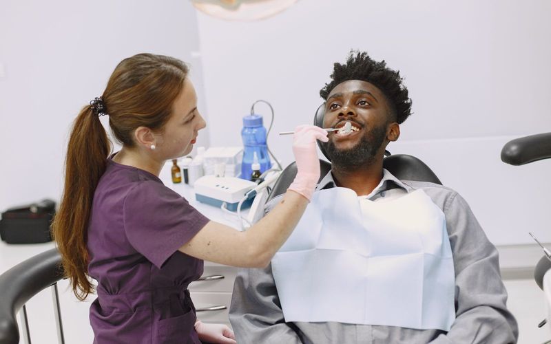 A dentist examining a male patient's teeth in a modern clinic setting