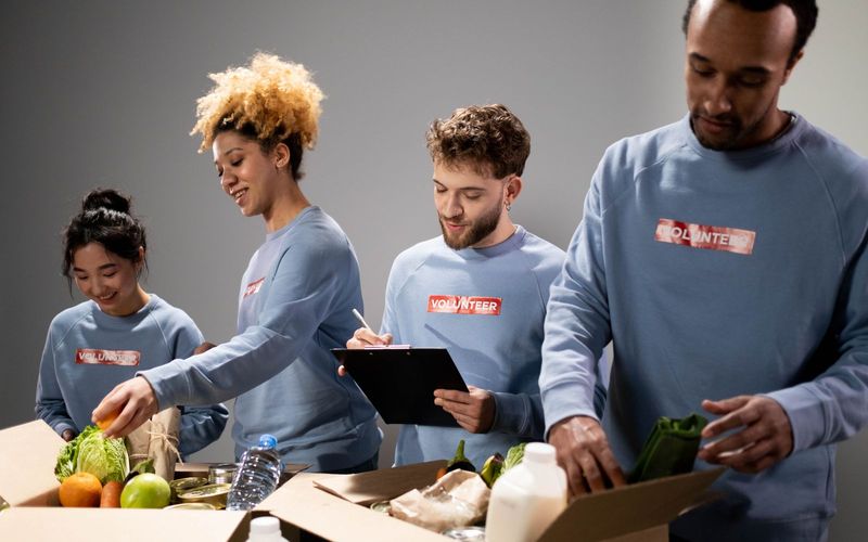 Four diverse volunteers pack food donations with teamwork and dedication