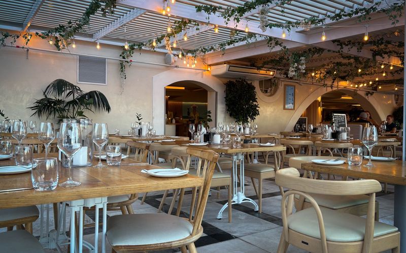Elegant indoor restaurant setting with wooden furniture, warm lighting, and decorative foliage
